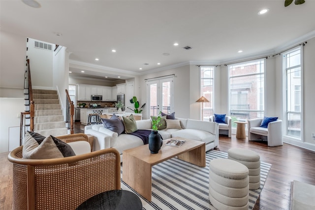 living room featuring a wealth of natural light, ornamental molding, and visible vents