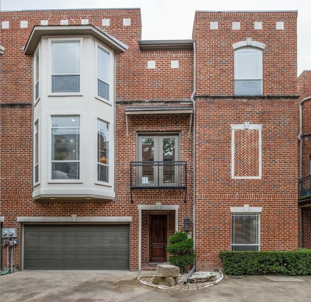 townhome / multi-family property featuring brick siding, an attached garage, driveway, and french doors