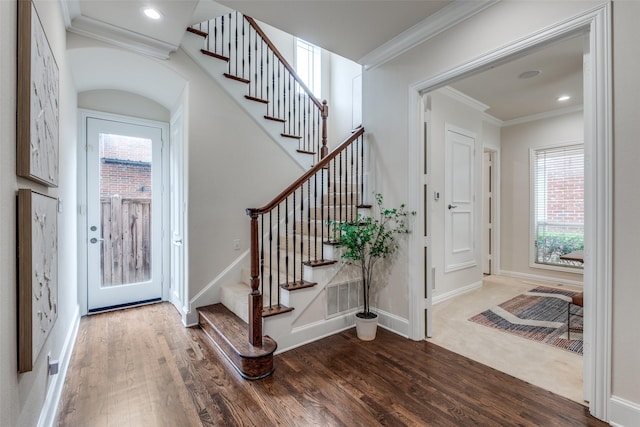 entryway with ornamental molding, stairs, wood finished floors, and a healthy amount of sunlight
