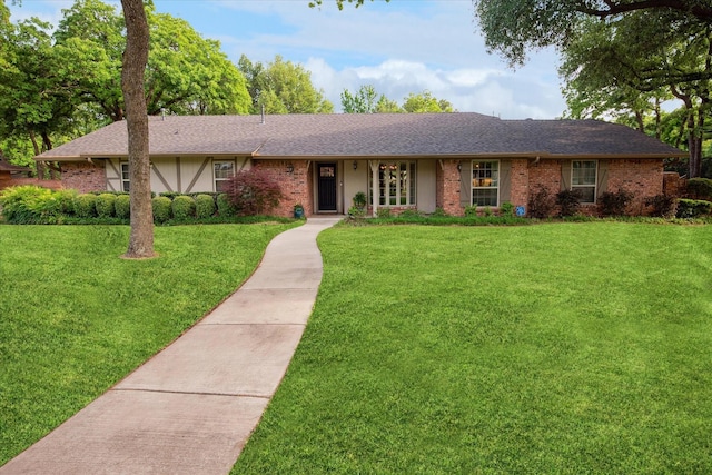 single story home featuring brick siding, roof with shingles, and a front yard