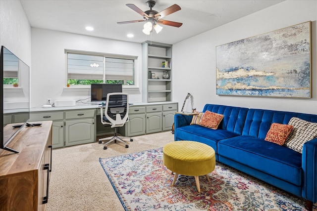 home office featuring built in study area, a ceiling fan, and light colored carpet