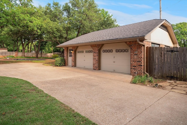 garage featuring fence and driveway