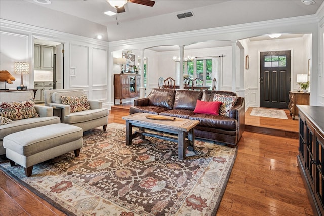 living room featuring a decorative wall, arched walkways, decorative columns, visible vents, and hardwood / wood-style flooring