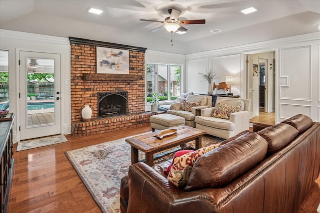 living area with a ceiling fan, wood finished floors, and a fireplace