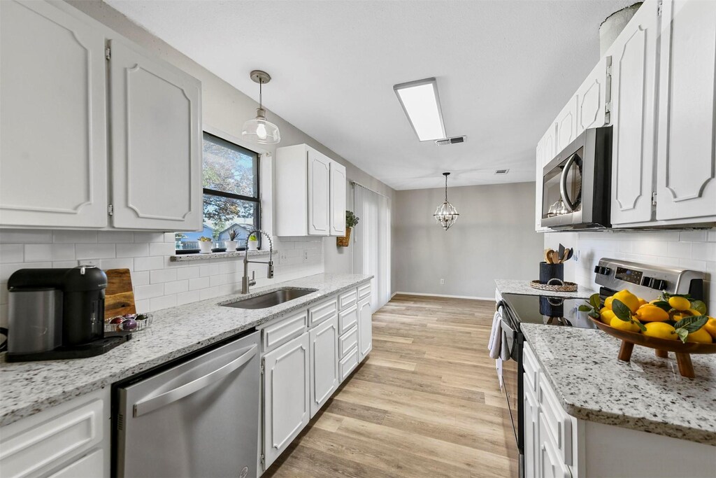 436 Fox Dr, Saginaw, TX 76179 - kitchen with light wood-style floors, baseboards, tasteful backsplash, a sink, and appliances with stainless steel finishes