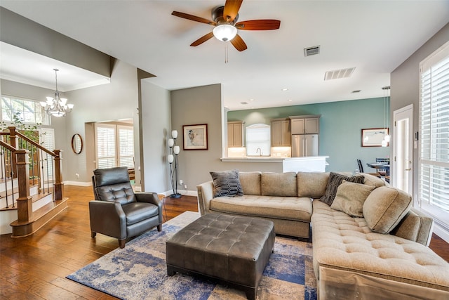 living area with visible vents, baseboards, ceiling fan with notable chandelier, and hardwood / wood-style flooring