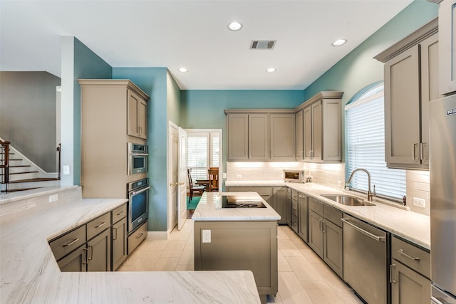 kitchen featuring a sink, appliances with stainless steel finishes, backsplash, and light stone counters
