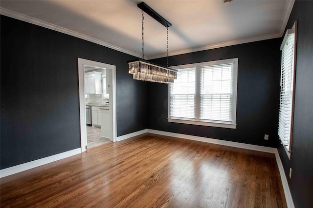 unfurnished dining area featuring crown molding, baseboards, and wood finished floors