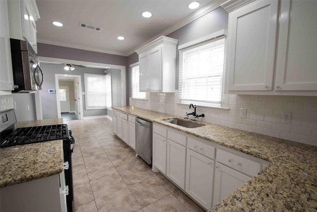 kitchen with a sink, appliances with stainless steel finishes, decorative backsplash, and white cabinetry