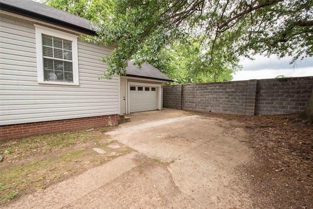 garage featuring fence and concrete driveway