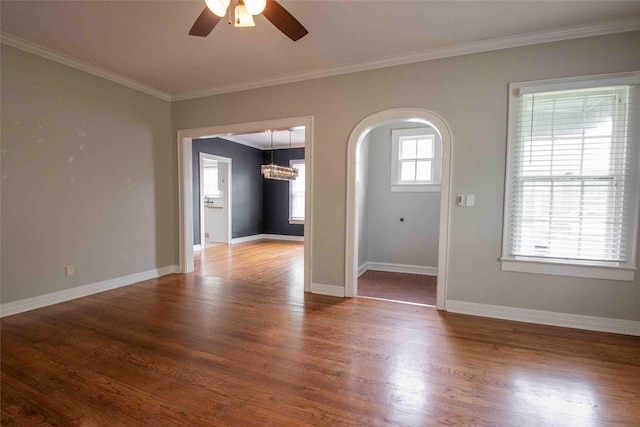 empty room with crown molding, arched walkways, wood finished floors, and ceiling fan with notable chandelier