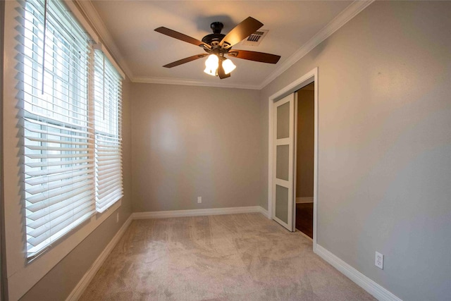 unfurnished room featuring light colored carpet, a ceiling fan, baseboards, visible vents, and ornamental molding
