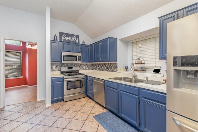 kitchen featuring a sink, appliances with stainless steel finishes, blue cabinets, and vaulted ceiling