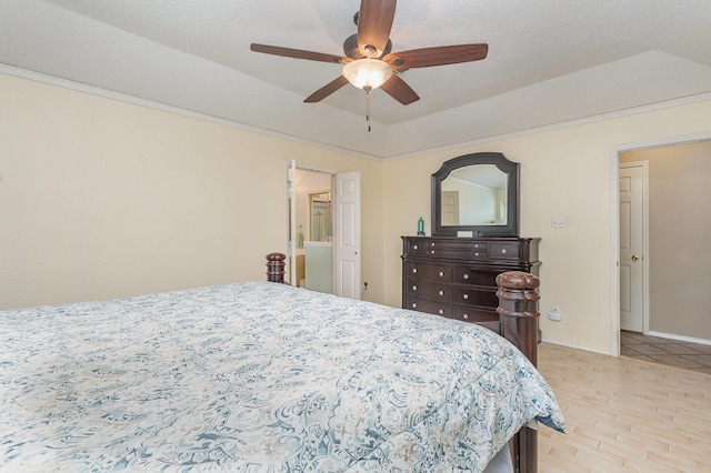 bedroom with baseboards, ceiling fan, a textured ceiling, a tray ceiling, and light wood finished floors