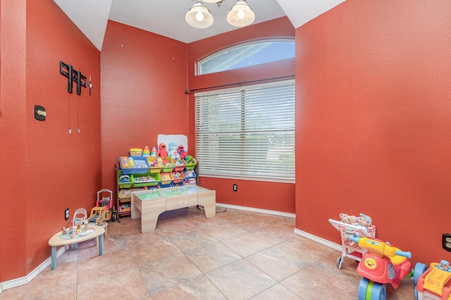 game room with baseboards, a textured wall, and tile patterned flooring