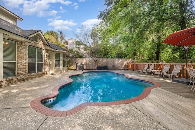 view of swimming pool with a fenced in pool, a fenced backyard, a wooden deck, and a patio