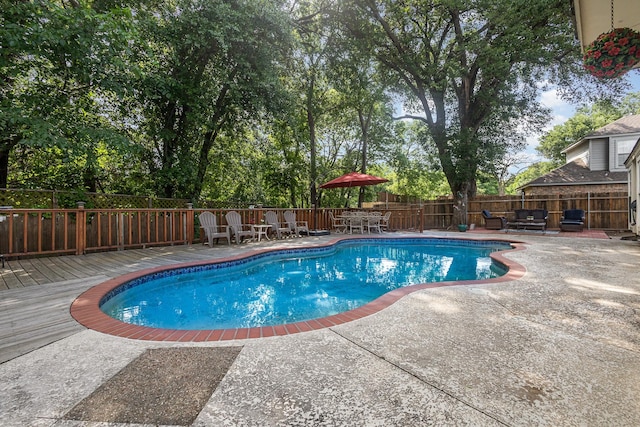 view of pool with a wooden deck, outdoor dining area, a fenced backyard, a patio, and a fenced in pool