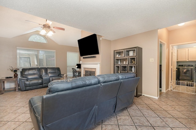 living area with washer / clothes dryer, light tile patterned flooring, ceiling fan, and a fireplace