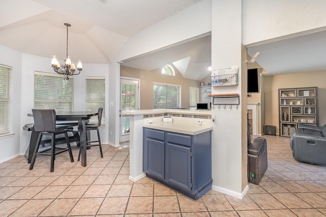 kitchen featuring blue cabinets, a chandelier, light countertops, lofted ceiling, and light tile patterned flooring