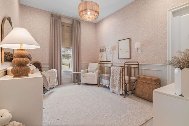 bedroom featuring carpet, a decorative wall, a wainscoted wall, and a nursery area