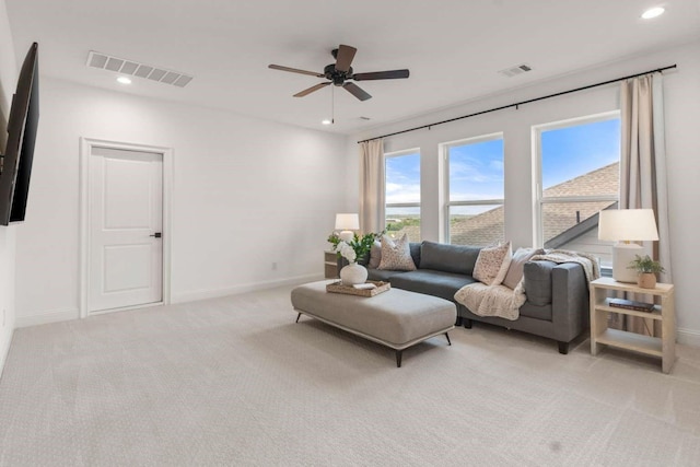 living area featuring a ceiling fan, baseboards, visible vents, and light carpet