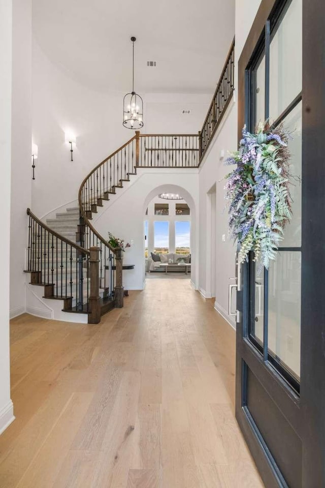 14336 Capridge Rd, Fort Worth, TX 76008 - foyer featuring arched walkways, stairway, wood finished floors, a chandelier, and a towering ceiling