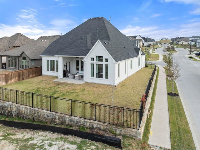 rear view of house with an outdoor living space, roof with shingles, a lawn, a patio area, and a fenced backyard