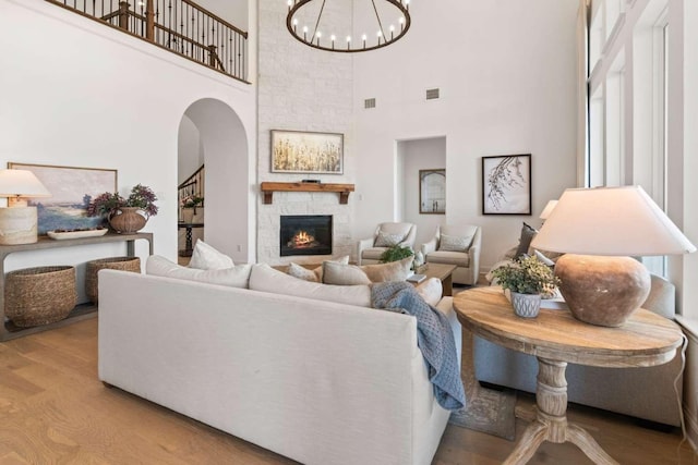 14336 Capridge Rd, Fort Worth, TX 76008 - living area with a towering ceiling, a stone fireplace, arched walkways, a chandelier, and wood finished floors