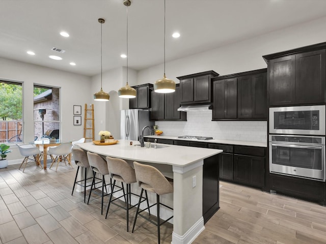 kitchen featuring a sink, dark cabinets, stainless steel appliances, and visible vents