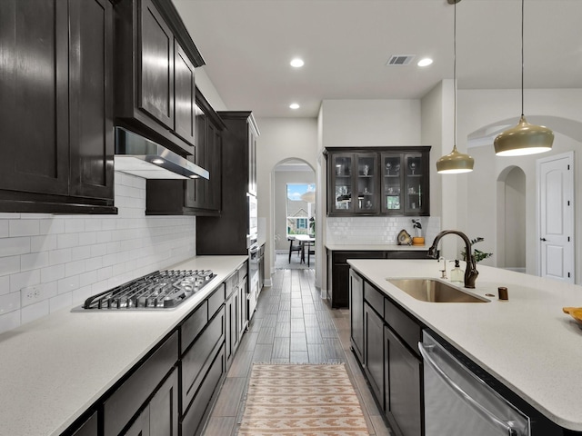 kitchen with appliances with stainless steel finishes, a sink, arched walkways, under cabinet range hood, and visible vents