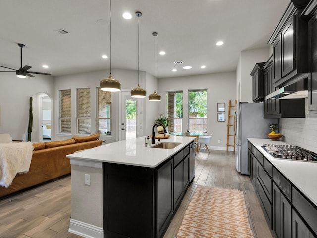kitchen with a sink, appliances with stainless steel finishes, dark cabinets, and light countertops