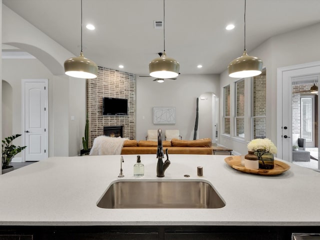 kitchen with decorative light fixtures, arched walkways, open floor plan, and a sink