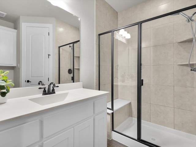 bathroom with vanity, a stall shower, and visible vents