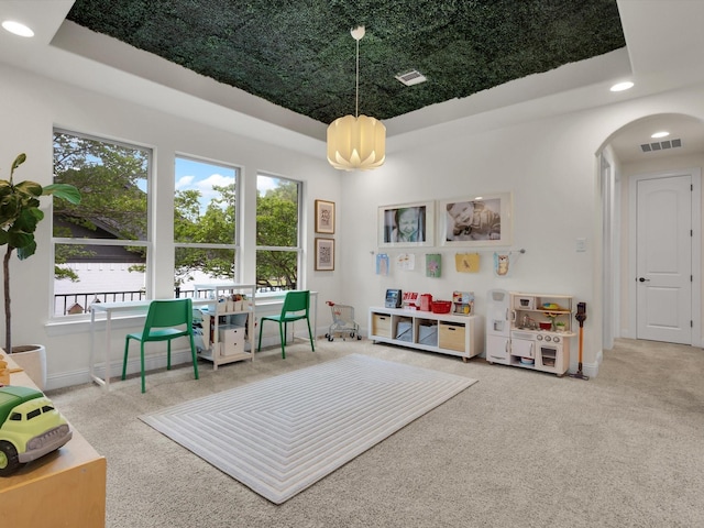 rec room featuring visible vents, carpet floors, and a tray ceiling