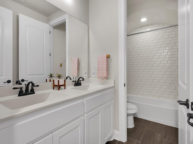 full bathroom featuring double vanity, a sink, shower / bath combination, and toilet