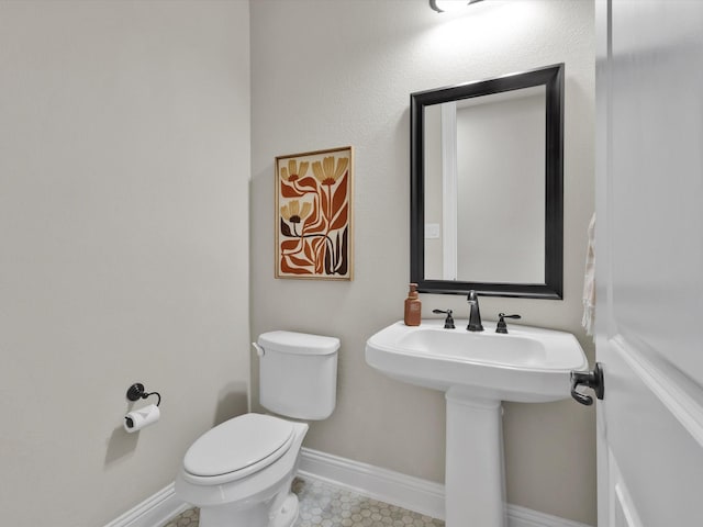 half bath featuring toilet and baseboards