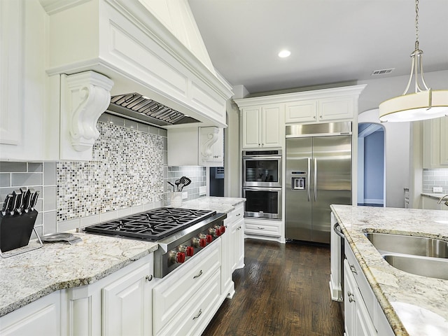 kitchen with appliances with stainless steel finishes, tasteful backsplash, light stone countertops, a sink, and white cabinetry