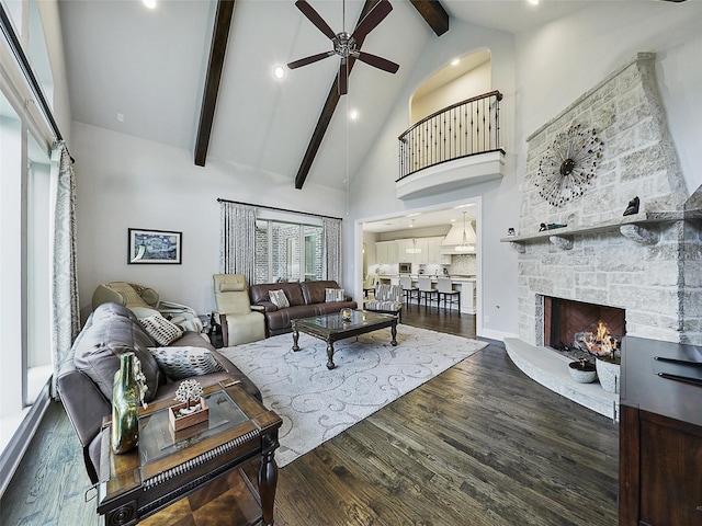 living room featuring a ceiling fan, a fireplace, beam ceiling, wood finished floors, and high vaulted ceiling