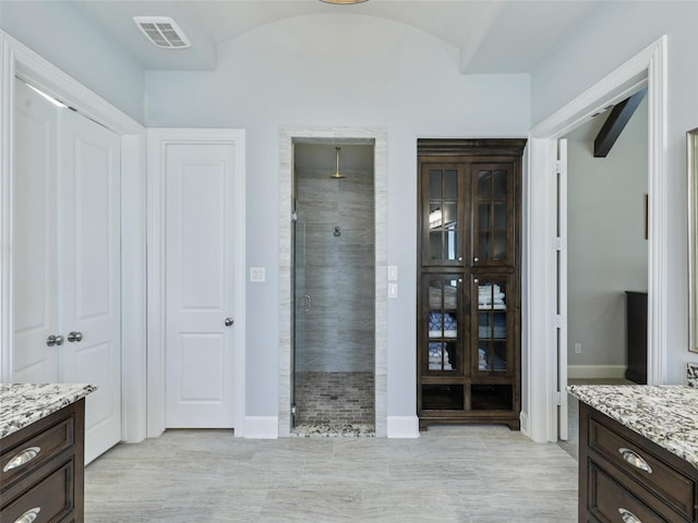 bathroom featuring visible vents, baseboards, vanity, and a shower stall