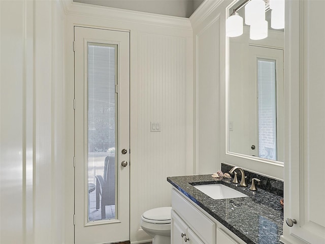 half bathroom with vanity, a decorative wall, and toilet