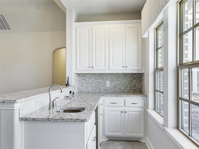 kitchen featuring visible vents, a sink, white cabinetry, and a peninsula