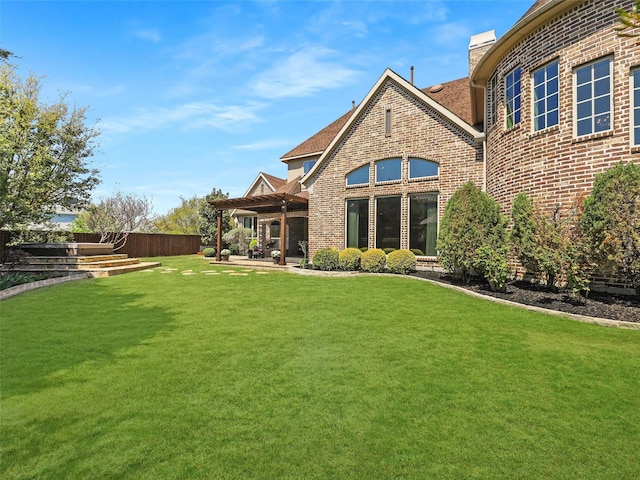 back of property featuring brick siding, a patio area, a yard, and a chimney