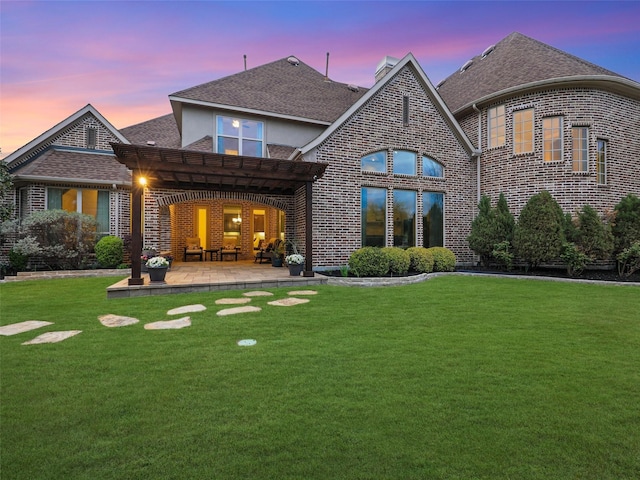 12643 Canyon Oaks Dr, Frisco, TX 75033 - back of house at dusk with a patio area, a pergola, brick siding, and a lawn