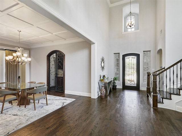 entryway featuring arched walkways, a chandelier, wood finished floors, stairway, and coffered ceiling