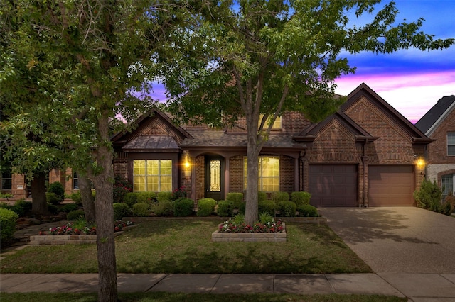 view of front facade with an attached garage, concrete driveway, a front yard, and brick siding