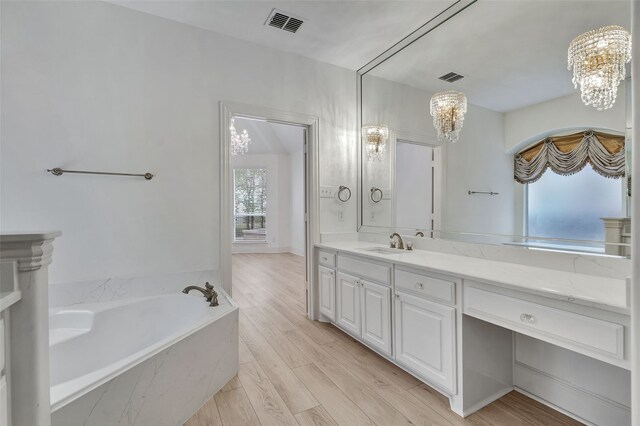 bathroom featuring vanity, a garden tub, visible vents, wood finished floors, and a notable chandelier
