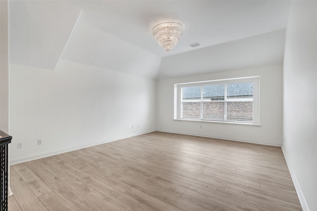spare room with baseboards, an inviting chandelier, light wood-style flooring, and visible vents