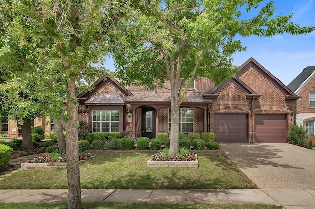 view of front facade with brick siding, a garage, driveway, and a front yard
