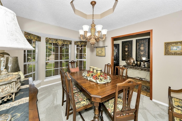 carpeted dining space featuring a textured ceiling, a chandelier, and baseboards
