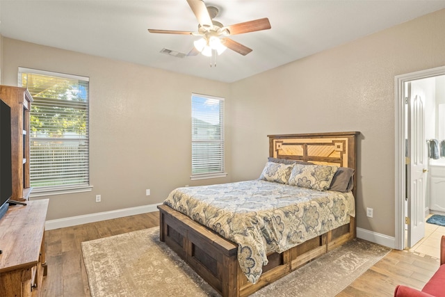 bedroom featuring baseboards, wood finished floors, and visible vents